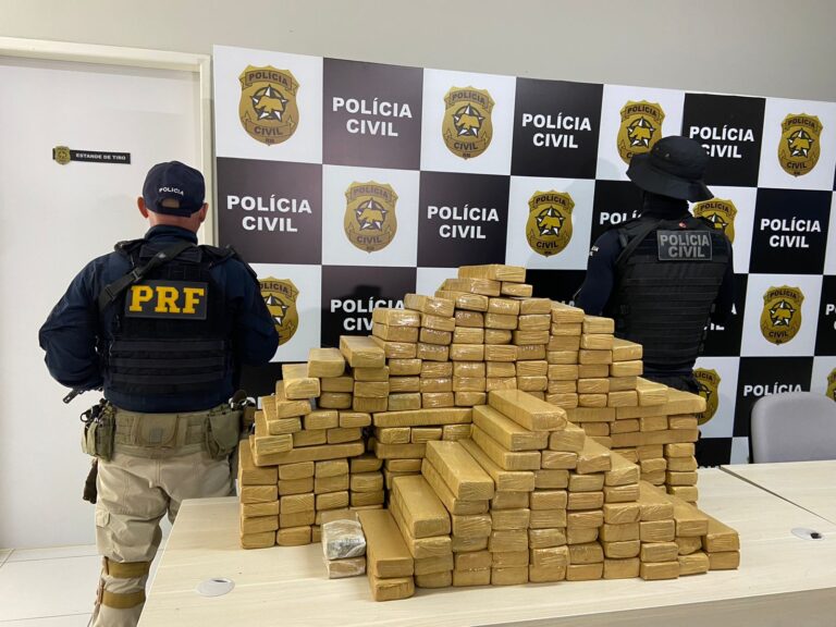 Imagens de policiais militares ao lado de uma pilha de tabletes de maconha apreendidos.