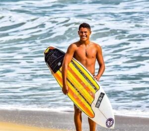 Imagem do jovem saindo do mar segurança o prancha de surf.