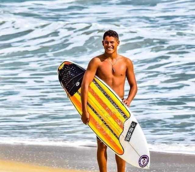 Imagem do jovem saindo do mar segurança o prancha de surf.