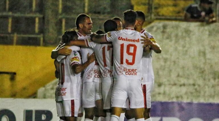 Imagem de jogadores do América abraçados em campo em comemoração.