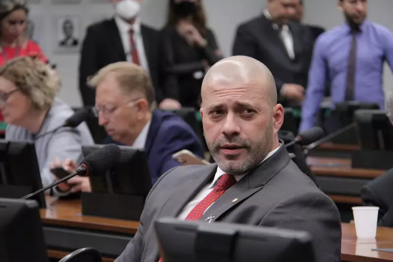 Imagem do ex-deputado Daniel Silveira sentado na sala de comissões.