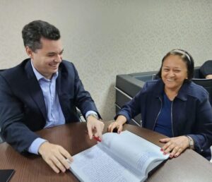 Imagem da governadora Fátima Bezerra sentada à mesa com vice-governadora Walter Alves na transmissão do cargo.