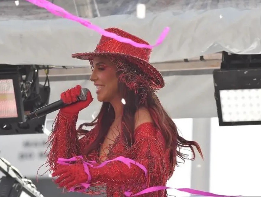 Imagem de Ivete com um figurino vermelho em cima do trio elétrico.