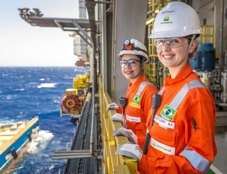 Imagem de duas técnicas da Petrobras prosando pra foto em plataforma.