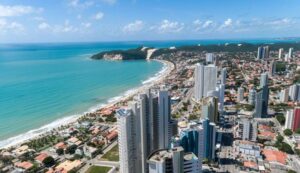 Ônibus urbano em avenida movimentada no Rio Grande do Norte com paisagem de prédios e céu azul