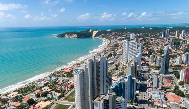 Ônibus urbano em avenida movimentada no Rio Grande do Norte com paisagem de prédios e céu azul